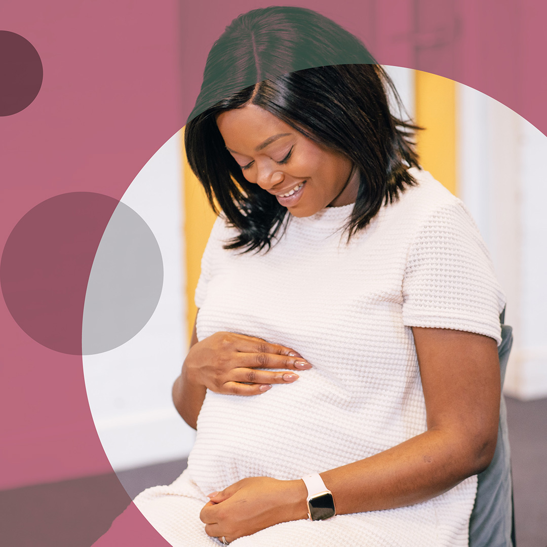 Pregnant person looking and smiling at their pregnancy bump