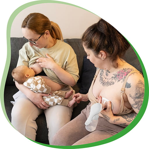 One mum breastfeeding while the other mum expresses