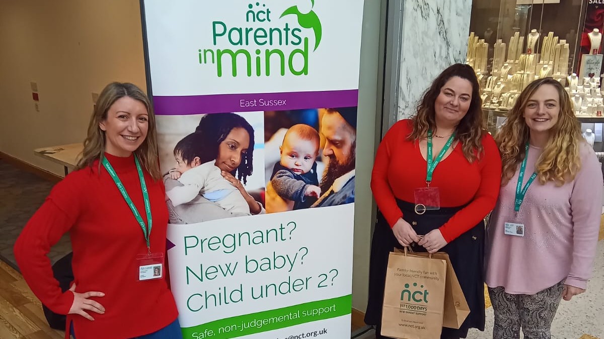 Group of Parents in Mind volunteers standing in front of a display banner