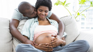 Dad hugging a pregnant mum on a sofa