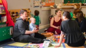 Parents sitting in a circle with their babies in an indoor play session