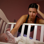 mum patting baby in cot