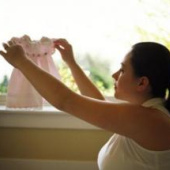 Woman holding baby clothes up to the window