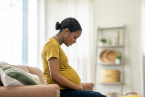 Pregnant woman sitting on a sofa and looking at her tummy