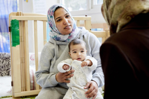 Mum wearing hijab holding baby on her lap