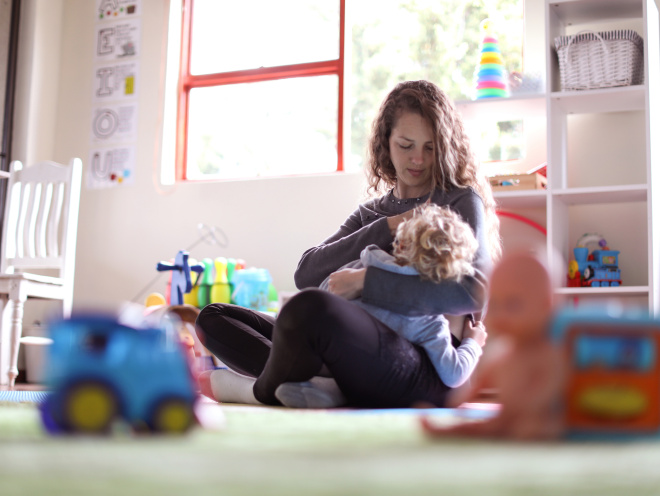 Parent breastfeeding child in playroom