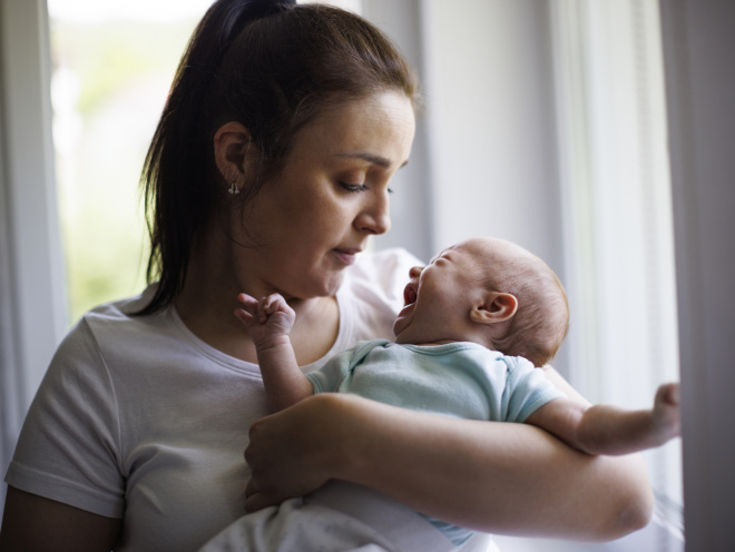 Parent holding a crying baby and looking concerned