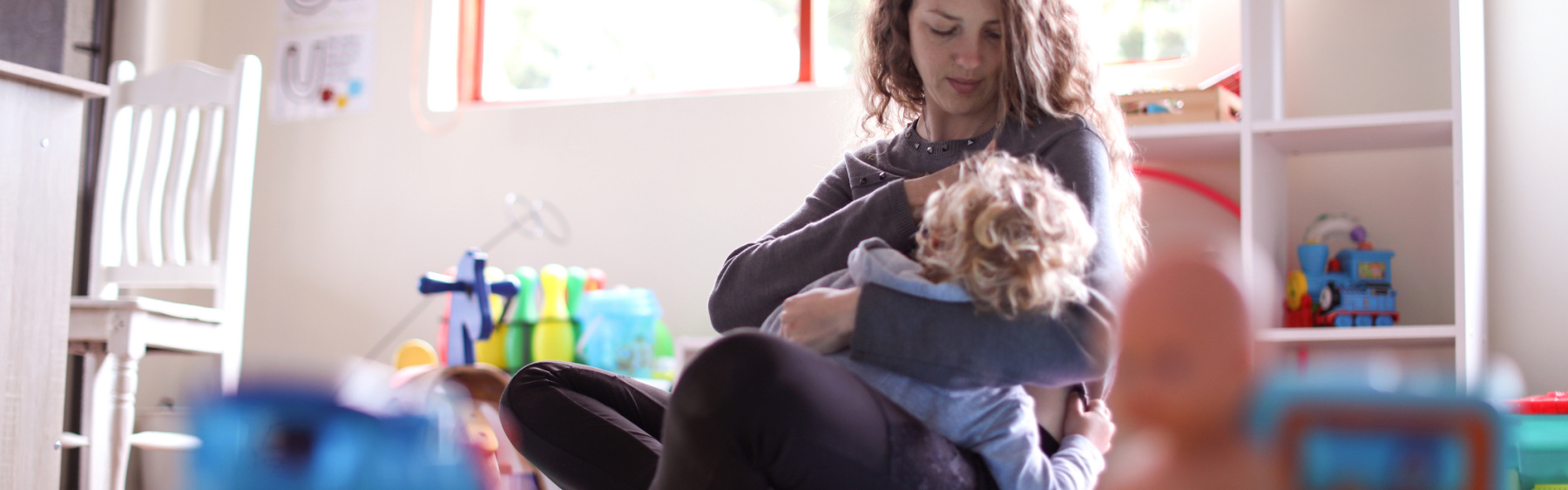 Parent breastfeeding child in playroom