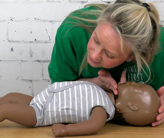 A person checking a baby doll for a heartbeat