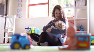 Parent breastfeeding child in playroom