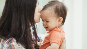 Parent kissing baby on the forehead