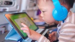 Young child playing on an iPad wearing headphones