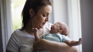 Parent holding a crying baby and looking concerned