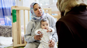 Mum wearing hijab holding baby on her lap