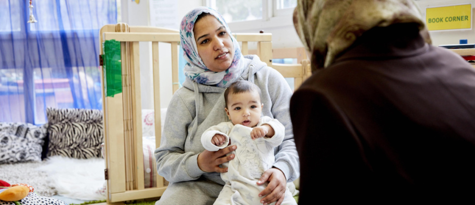 Mum wearing hijab holding baby on her lap